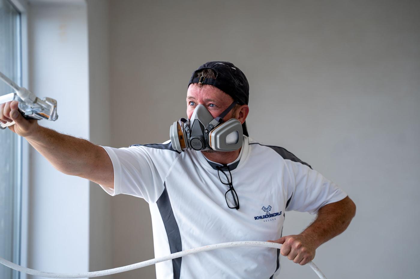 Schilder met pet en masker aan het spuiten